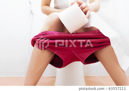 Women wearing white sleepwear, Sitting on the toilet Hand holding the stomach,standing in the toilet, Holding a toilet paper, bent, stomachache health care concept Women wearing white sleepwear, Sitting on the toilet Hand holding the stomach,standing in the toilet, Holding a toilet paper, bent, stomachache health care concept 63557211