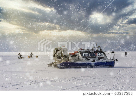 People travel, dogsledding on the ice of frozen Baikal Lake in a safe and comfortable Hivus hovercraft. 63557593