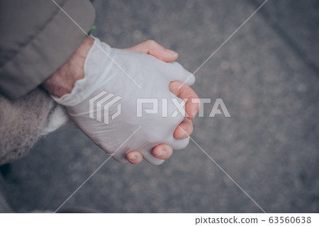 Two hands of a couple one in a plastic glove virus 63560638
