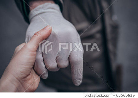 Two hands of a couple one in a plastic glove virus 63560639