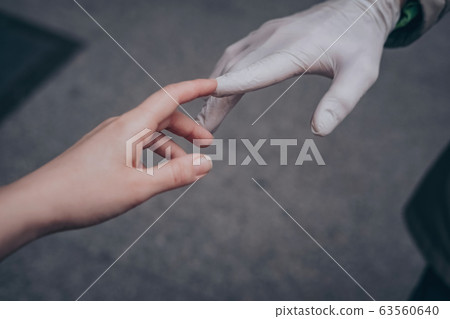 Two hands of a couple one in a plastic glove virus 63560640
