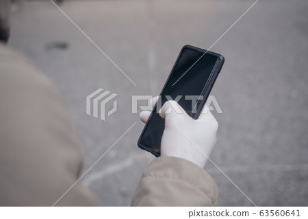 Man holding phone in a rubber glove virus 63560641