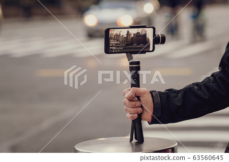 Man taking photos and videos with phone and 63560645