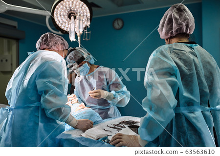 Surgeons and paramedic in mask and operating patient, a professional team of doctors in a modern operating room Surgeons and paramedic in mask and operating patient, a professional team of doctors in a modern operating room 63563610