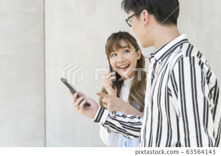 年輕的男人和女人在戶外的智能手機 年輕的男人和女人在戶外的智能手機 63564143