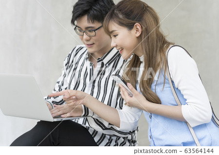 年輕的男人和女人在戶外看電腦 年輕的男人和女人在戶外看電腦 63564144
