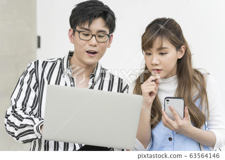 年輕的男人和女人在戶外看電腦 年輕的男人和女人在戶外看電腦 63564146