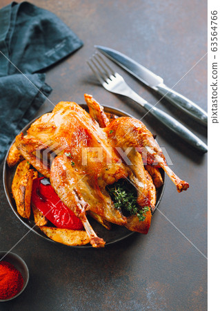 Roasted guinea fowl with herbs and olive oil on a dish with a garnish of potatoes and red pepper. Roasted guinea fowl with herbs and olive oil on a dish with a garnish of potatoes and red pepper. 63564766