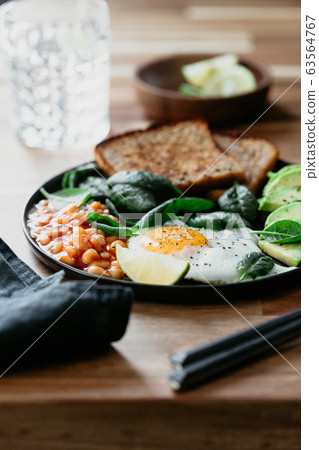 Fried egg, avocado, toasts, beans and fresh spinach. Healthy eating concept. Fried egg, avocado, toasts, beans and fresh spinach. Healthy eating concept. 63564767
