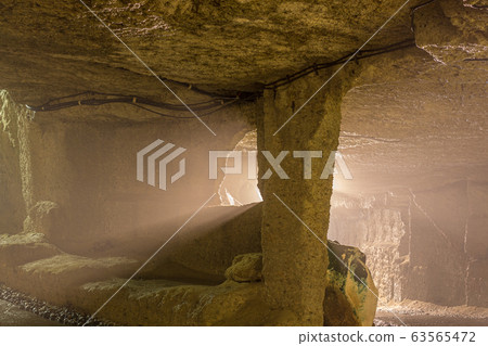 Long exposure image of light beams cutting through the damp underground haze, and rock pillar inside the Hanibe caves complex, Komatsu, Ishikawa Prefecture, Japan. 63565472