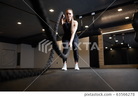 Focused Young Woman Working Out with Battle Ropes Focused Young Woman Working Out with Battle Ropes 63566278