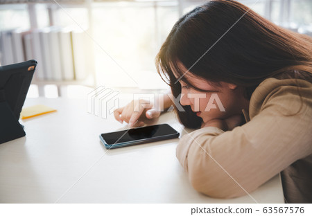 woman with chin on arm using smartphone woman with chin on arm using smartphone 63567576