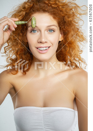 Smiling red-haired pretty girl massaging her forehead 63567808