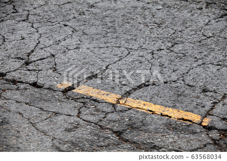 Cracked asphalt road with yellow dividing line 63568034