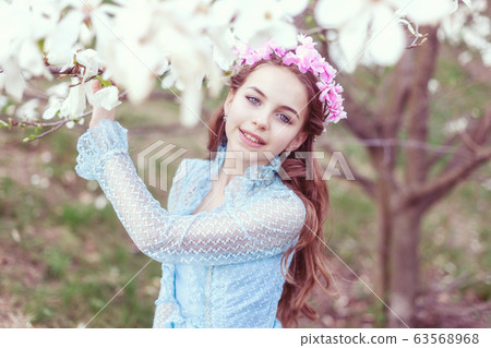 Cute girl stands near the magnolia tree. Cute girl stands near the magnolia tree. 63568968