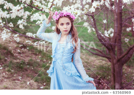 Portrait of a cute girl near a blooming magnolia. 63568969