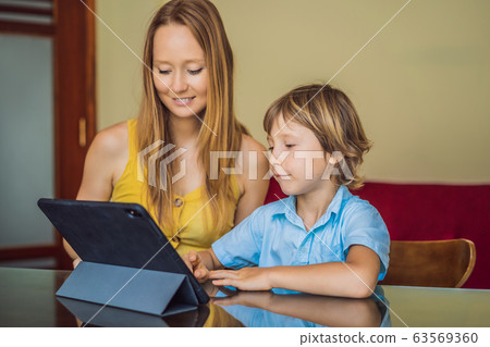 A boy studying online at home using a tablet. Mom helps him learn. Studying during quarantine 63569360