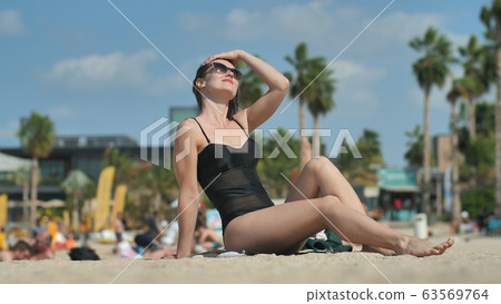 The girl on the beach in Dubai sunbathes on the beach. 63569764