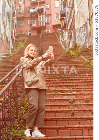 Woman takes selfie on the red stairs in Istanbul. 63570376