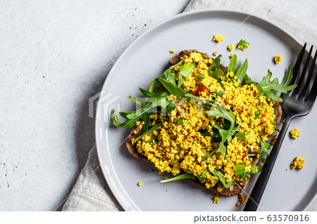 Tofu scramble toast with greens on rye bread. Tofu scramble toast with greens on rye bread. 63570916