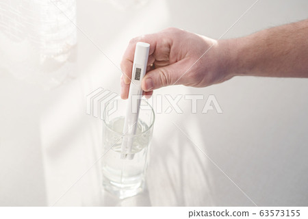 Man determines level of total dissolved solids or TDS in drinking water at home. Device shows 200 ppm of contaminant level which is considered the typical value in the scale of water TDS. Health care Man determines level of total dissolved solids or TDS in drinking water at home. Device shows 200 ppm of contaminant level which is considered the typical value in the scale of water TDS. Health care 63573155