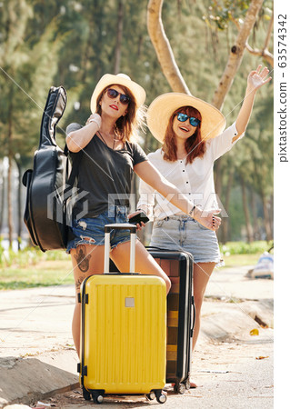 Young women trying to stop car Young women trying to stop car 63574342