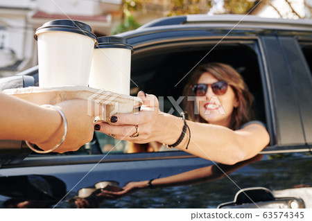 Waiter giving coffee cups to female driver 63574345