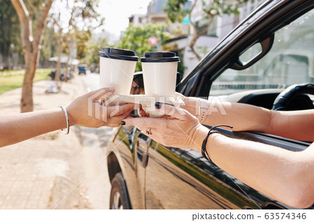 Female driver buying take out coffee Female driver buying take out coffee 63574346