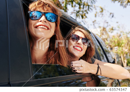 Cheerful women riding in car Cheerful women riding in car 63574347