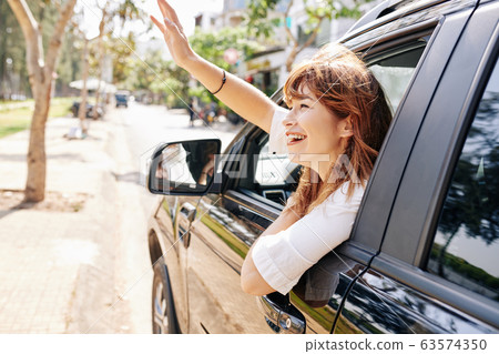 Woman i car waving to friend 63574350