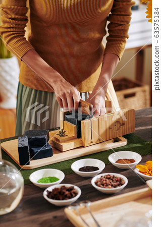Woman cutting loaf of black soap 63575184