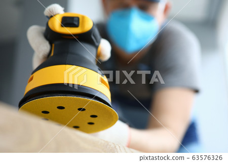 Male handy man hold yellow grinder with disc sander in hand closeup Male handy man hold yellow grinder with disc sander in hand closeup 63576326