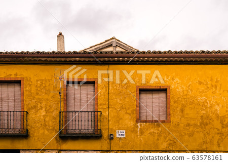 Traditional house with windows and balconies and a yellow plastered facade 63578161