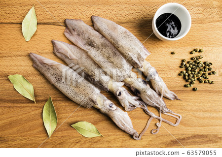 group of fresh squids next to a bowl with ink, group of fresh squids next to a bowl with ink, 63579055