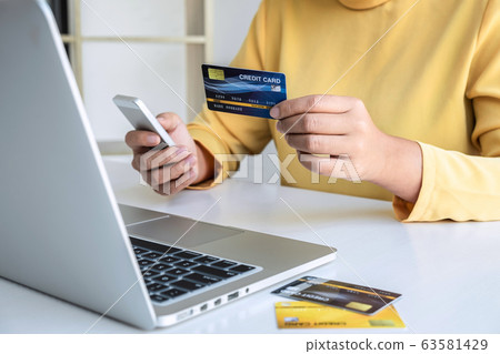 Woman using credit card and smartphone register 63581429