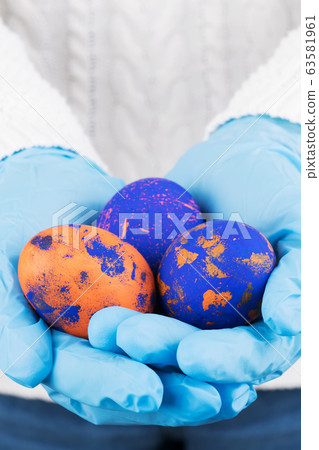 Easter time in quarantine concept. Female hands in blue medical gloves holding colored Easter eggs. Concept of Easter holyday and spring break during coronavirus Easter time in quarantine concept. Female hands in blue medical gloves holding colored Easter eggs. Concept of Easter holyday and spring break during coronavirus 63581961