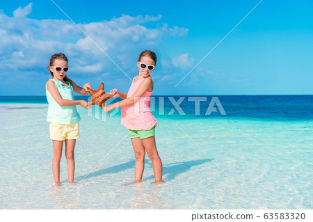 Two little happy girls have a lot of fun at tropical beach playing together Two little happy girls have a lot of fun at tropical beach playing together 63583320