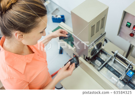 Worker checking textile label fresh from the printing machine 63584325
