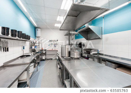 Modern restaurant kitchen with stainless steel kitchenware and equipment. Cooking with preparation tables, pans, pots, stoves. 63585763