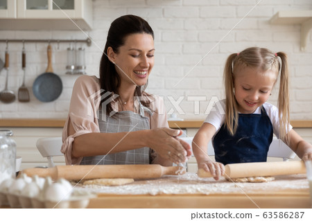 Happy mom and daughter baking pie at home together 63586287