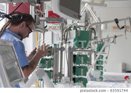 Male nurse checks the function of syringe infusion pump 63591744