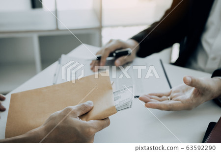 Businessman secretly giving a bribe by giving Businessman secretly giving a bribe by giving 63592290
