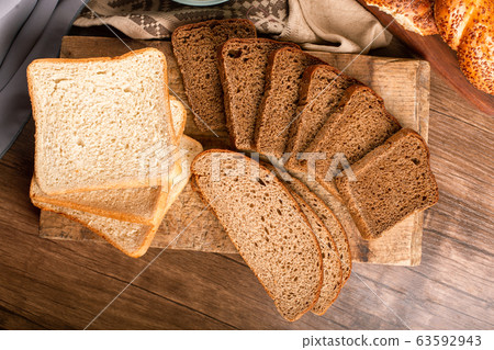 Tasty bagels with slices of bread and bowl of flour Tasty bagels with slices of bread and bowl of flour 63592943