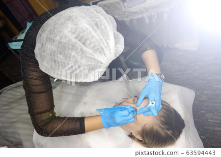 Professional Beautician Asian woman applying Tottoo, Brow Microblading to caucasian customer eyebrows to make permanent color makeup or tattooing line look real in beauty salon, copy space text logo Professional Beautician Asian woman applying Tottoo, Brow Microblading to caucasian customer eyebrows to make permanent color makeup or tattooing line look real in beauty salon, copy space text logo 63594443
