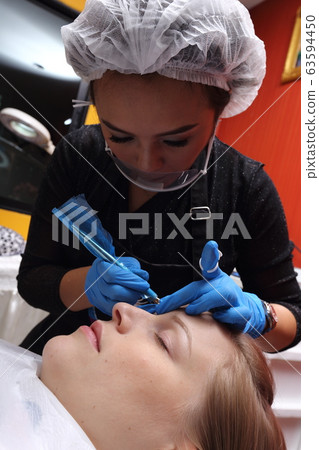 Professional Beautician Asian woman applying Tottoo, Brow Microblading to caucasian customer eyebrows to make permanent color makeup or tattooing line look real in beauty salon, copy space text logo Professional Beautician Asian woman applying Tottoo, Brow Microblading to caucasian customer eyebrows to make permanent color makeup or tattooing line look real in beauty salon, copy space text logo 63594450