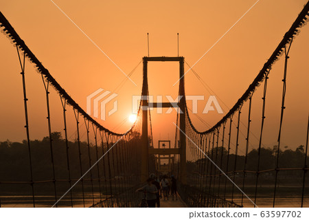 Silhouette view of the bicentennial rope bridge in sunset time in Tak province, Thailand. 63597702