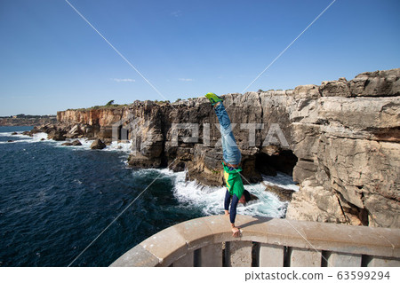 Man performs a handstand on the edge of view point in Portugal. Concept of risk, courage and brave 63599294