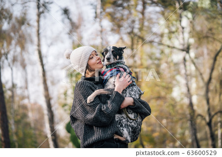 A girl is holding a mongrel dog in her arms. Caring for animals. A girl is holding a mongrel dog in her arms. Caring for animals. 63600529