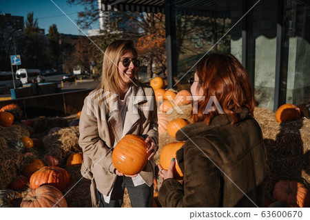 Girls holds pumpkins in hands. Outdoor photo. 63600670