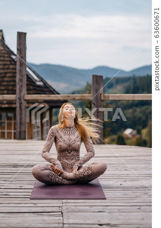 A woman sitting in lotus position at the morning on a fresh air. 63600671